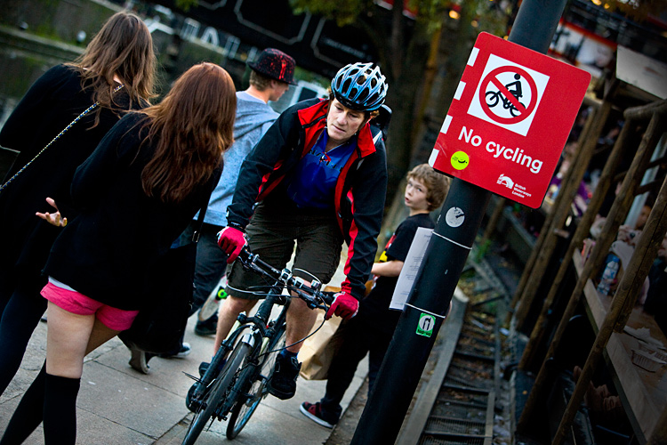 Cyclist On The Tow Path Pushing Through Pedestrians : Camden Lock : London