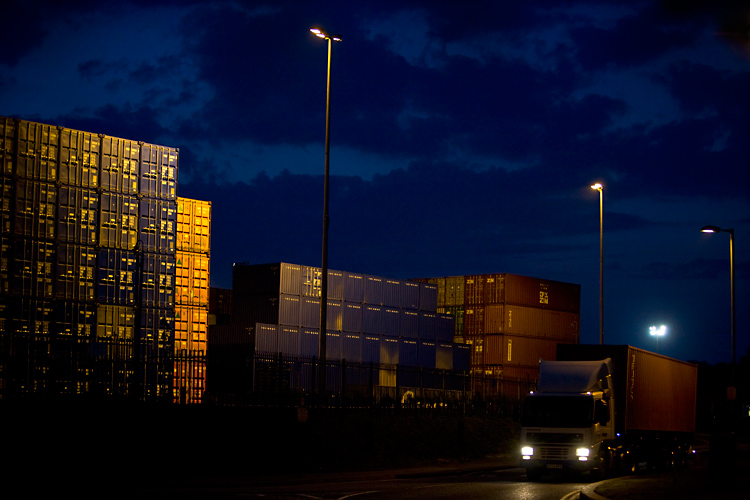 Night Falls but Global Trade Goes On : Containers Piled High and Leaving by Road : Felixstowe Docks : UK
